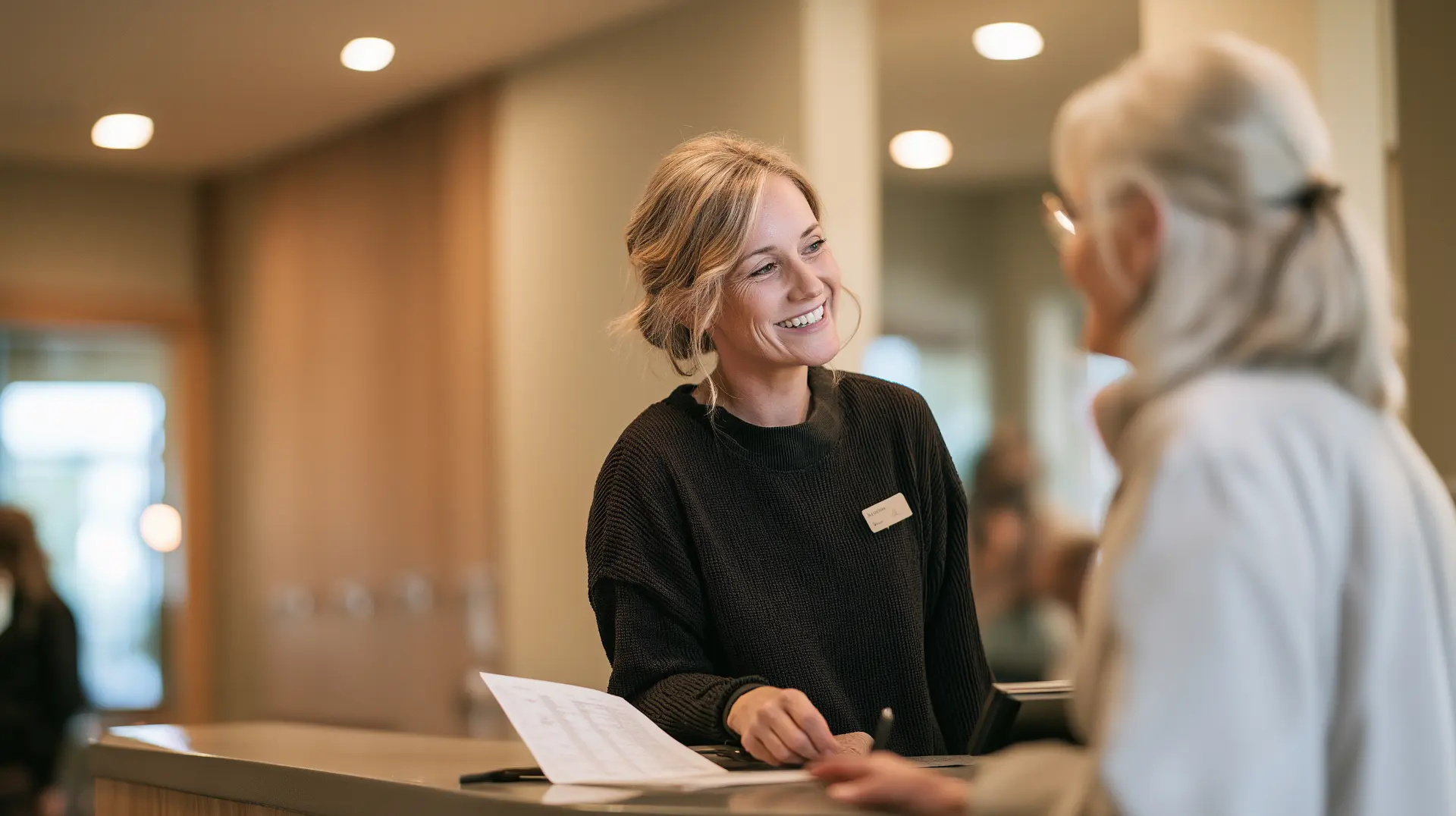 Patient reviewing a dental implant cost estimate with an office coordinator at the front desk