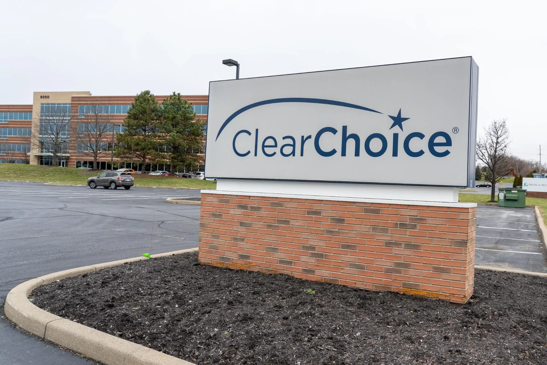 ClearChoice dental implant center monument sign with the blue star logo outside a brick office building, shown in a review of ClearChoice full-arch dental implants
