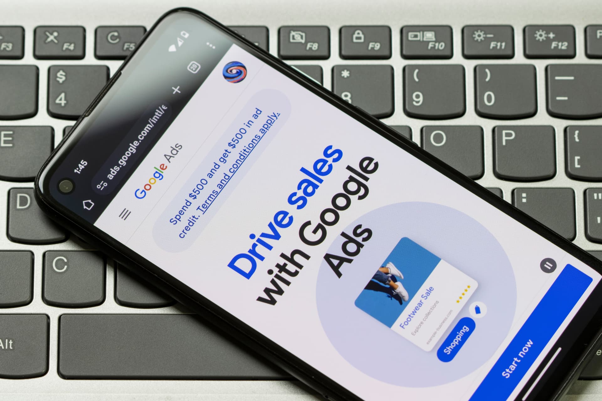 Smartphone resting on a laptop keyboard showing the Google Ads homepage, illustrating Google Local Services Ads for dental implant practices