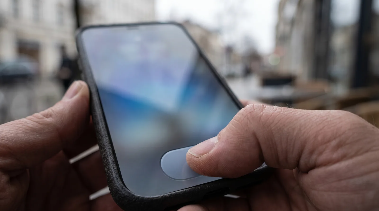Person filling out a short form on a phone, thumb over a large button, screen content blurred