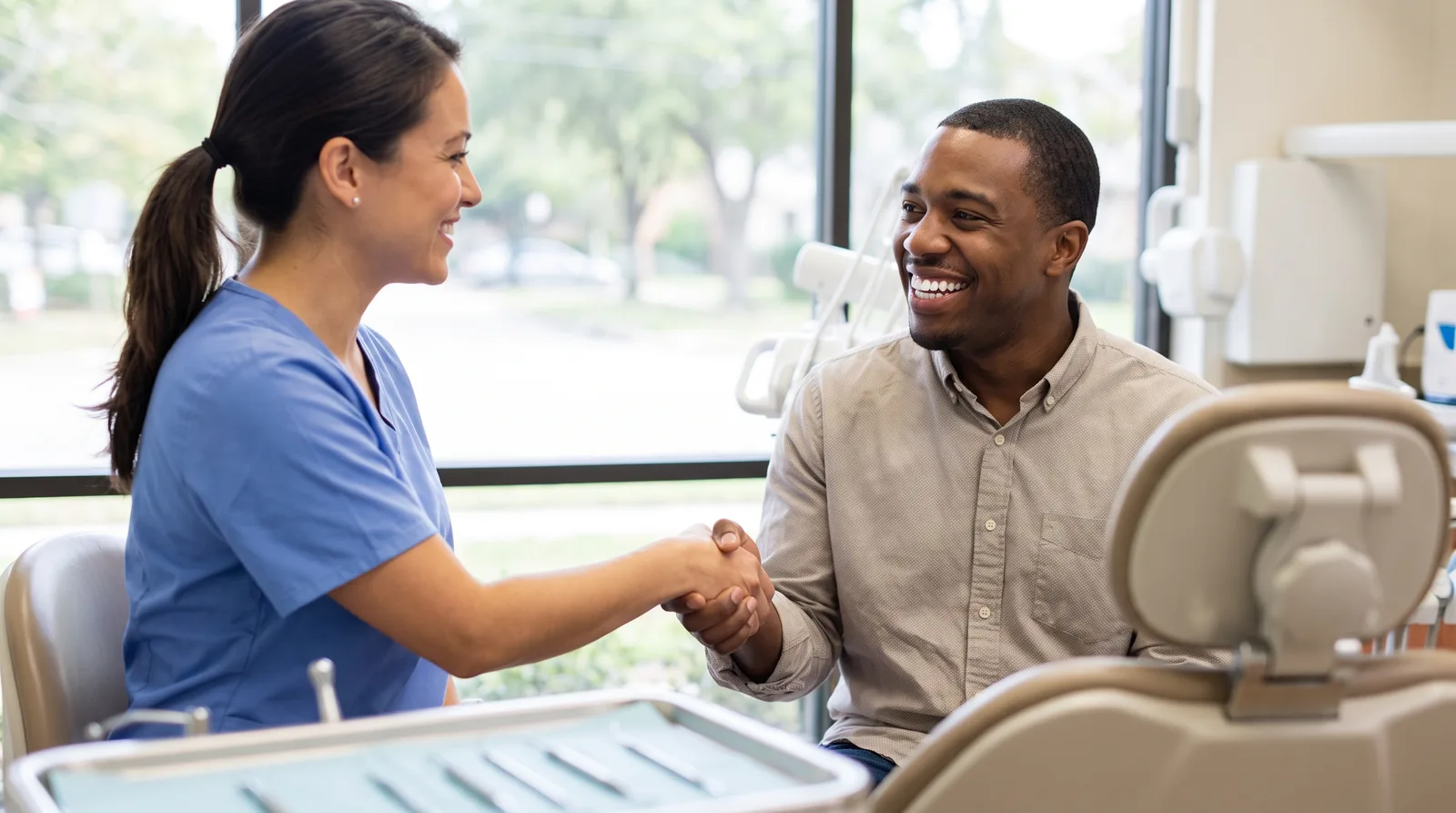 Dentist and patient shaking hands at the end of a final delivery visit, patient smiling with new teeth, bright operatory