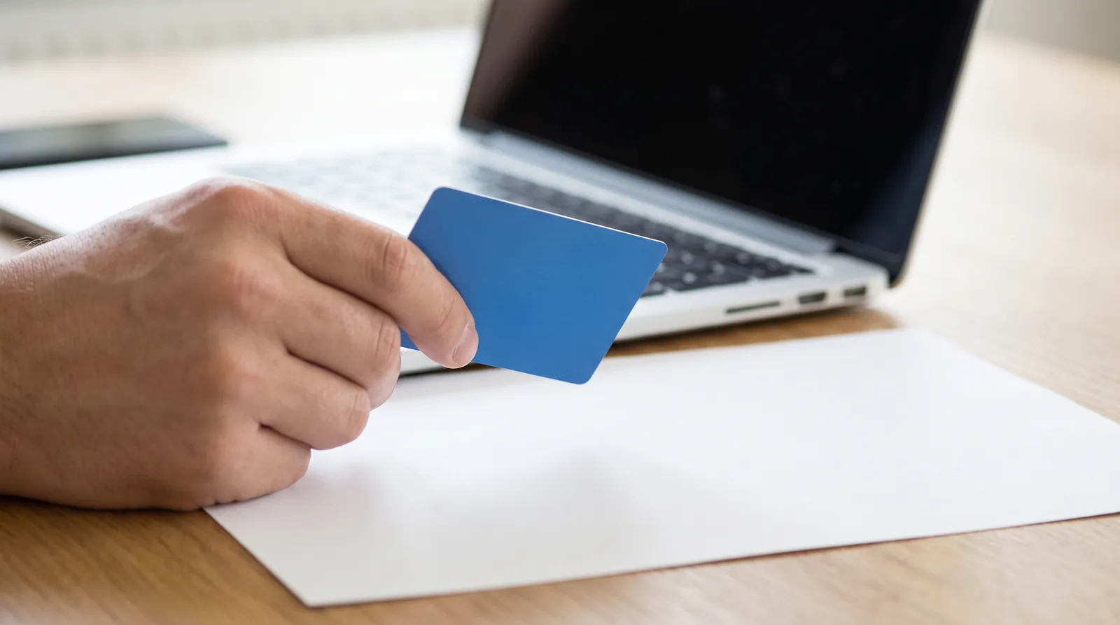 Person at a desk holding a health savings account debit card above a dental treatment estimate, laptop open beside them