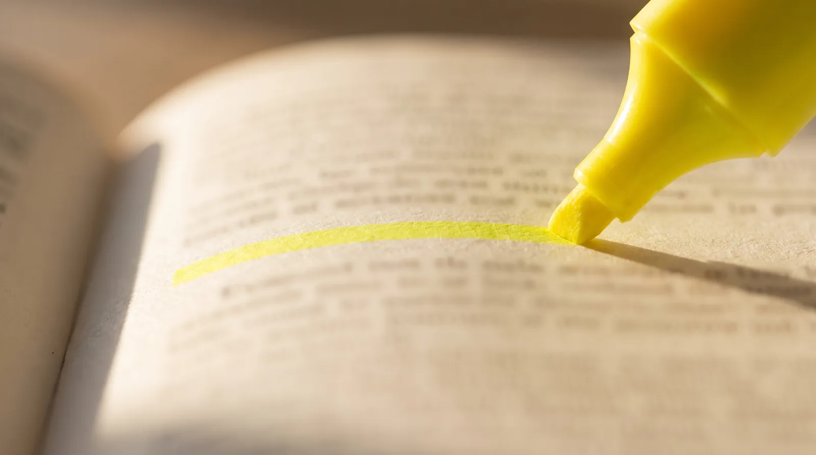 Close-up of a highlighter marking a line in a printed benefits booklet, the text softly out of focus