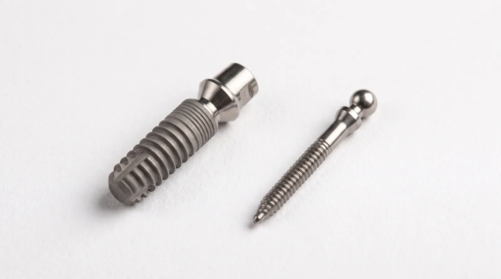 Standard dental implant and a mini dental implant side by side on a white surface showing the difference in diameter
